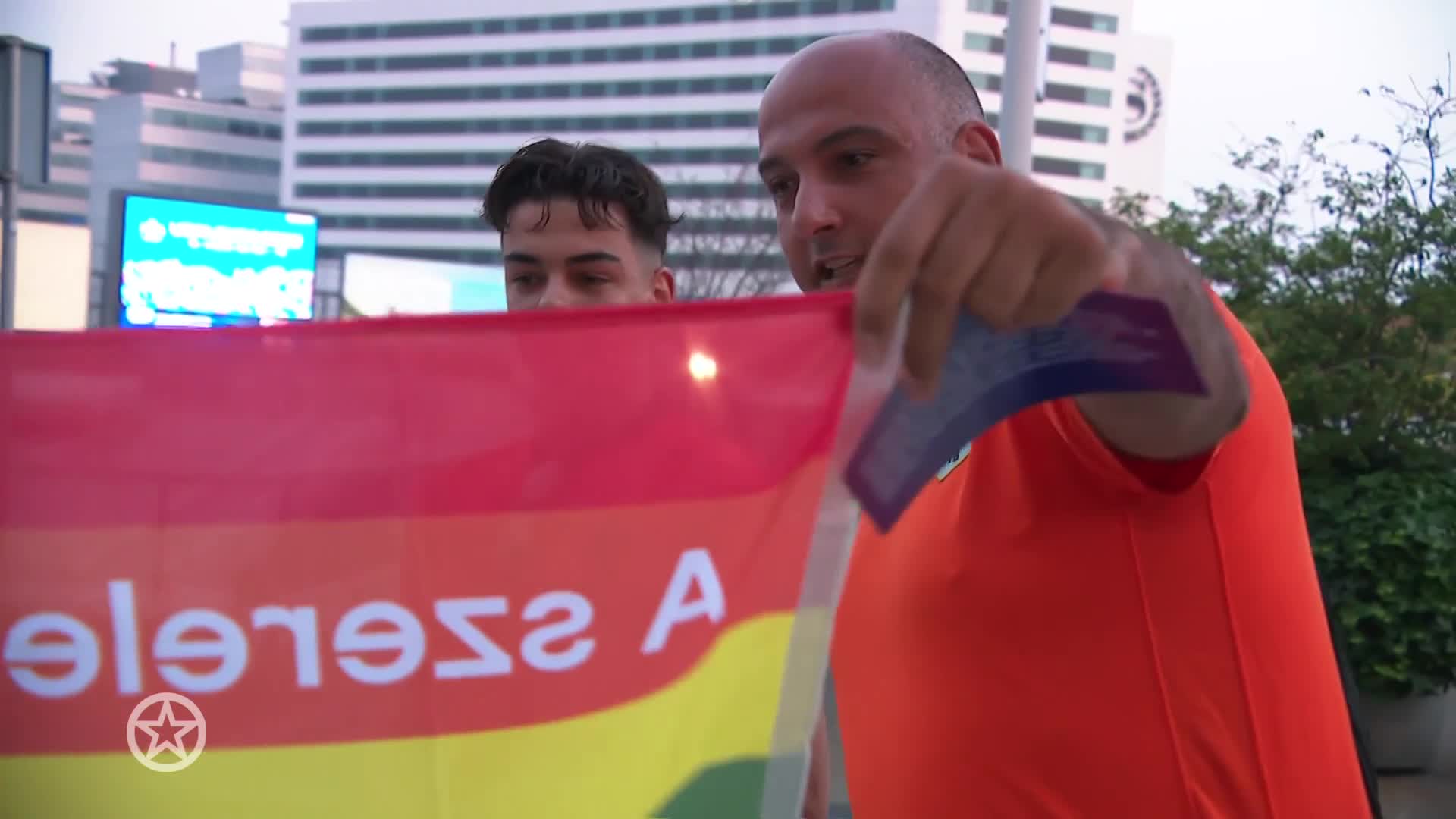 Klaas van Kruistum deelt regenboogvlaggen uit aan Oranjefans