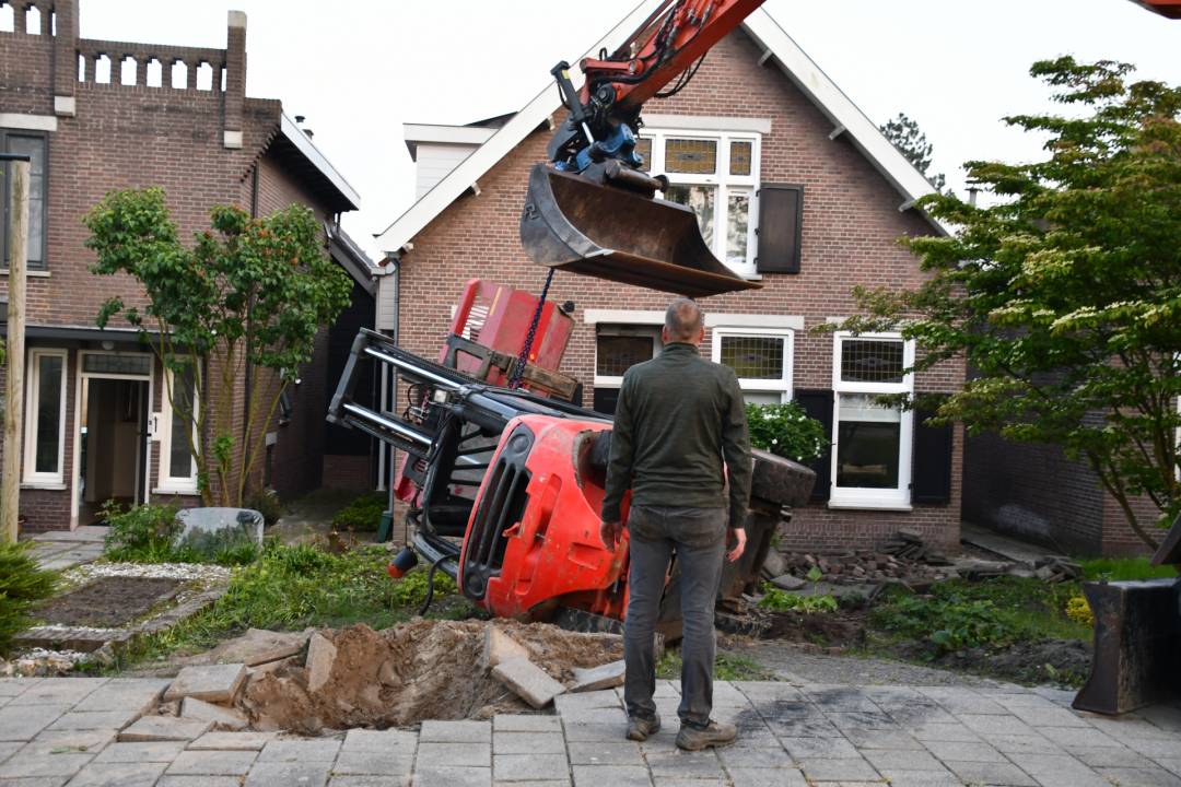 Heftruck op z'n kant in voortuin, bestuurder raakt bekneld