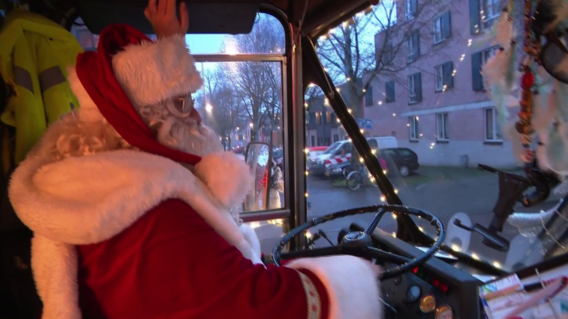 Kerstman rijdt in versierde bus door Arnhem om kinderen van minima een cadeautje te brengen