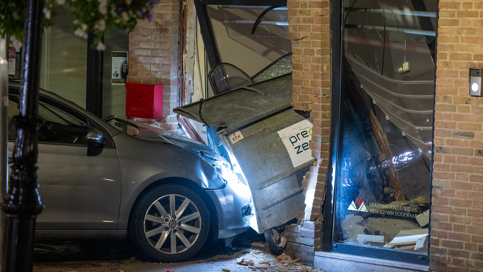 Auto ramt vuilniscontainer door gevel bij ramkraak op juwelier