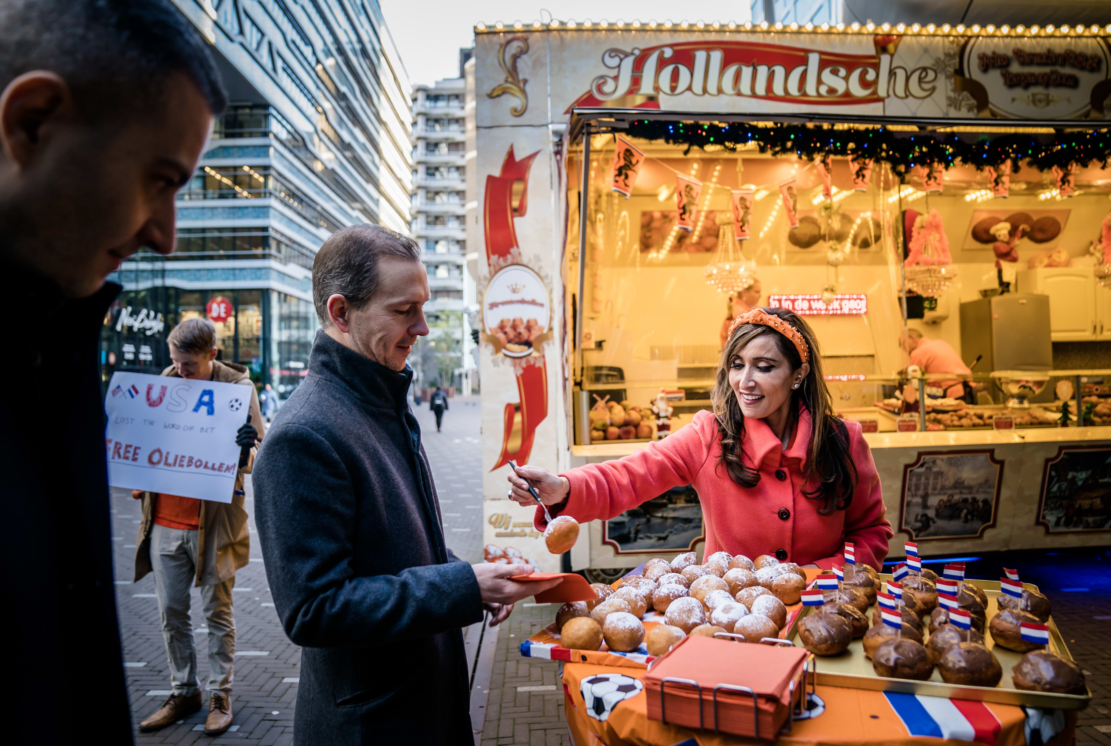 Ambassadeur VS deelt oliebollen uit op Den Haag CS na verliezen WK-weddenschap