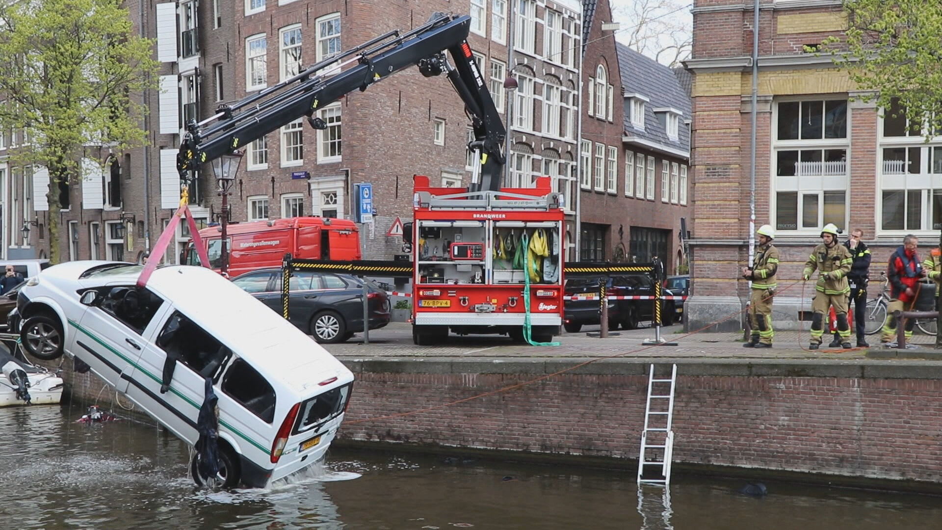 Busje met negen toeristen belandt in Amsterdamse gracht