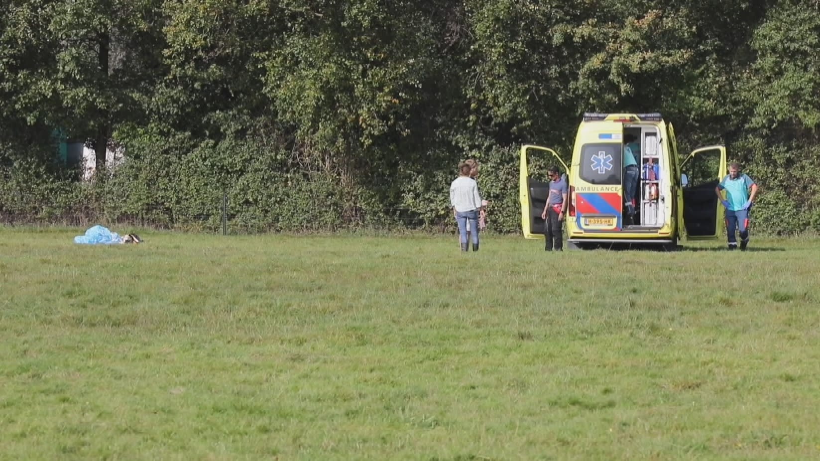 Parachutist stort neer in weiland, met spoed naar ziekenhuis gebracht