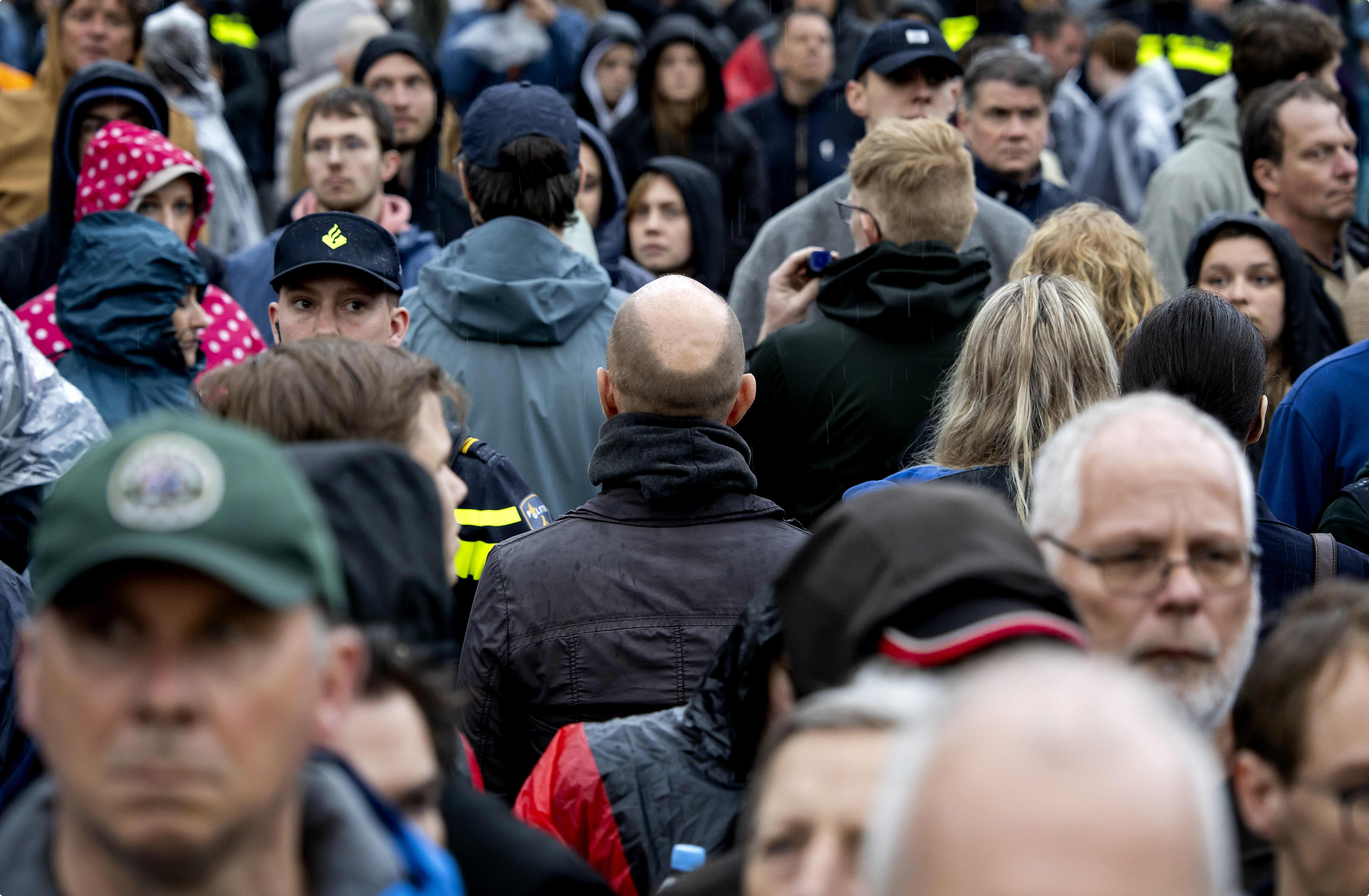 Meerdere mensen op Dam draaien Bosma rug toe tijdens kranslegging. Beeld: ANP