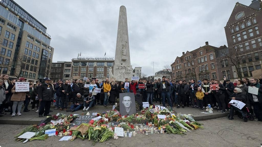 Betogers leggen bloemen neer rondom een grote foto van Navalny.