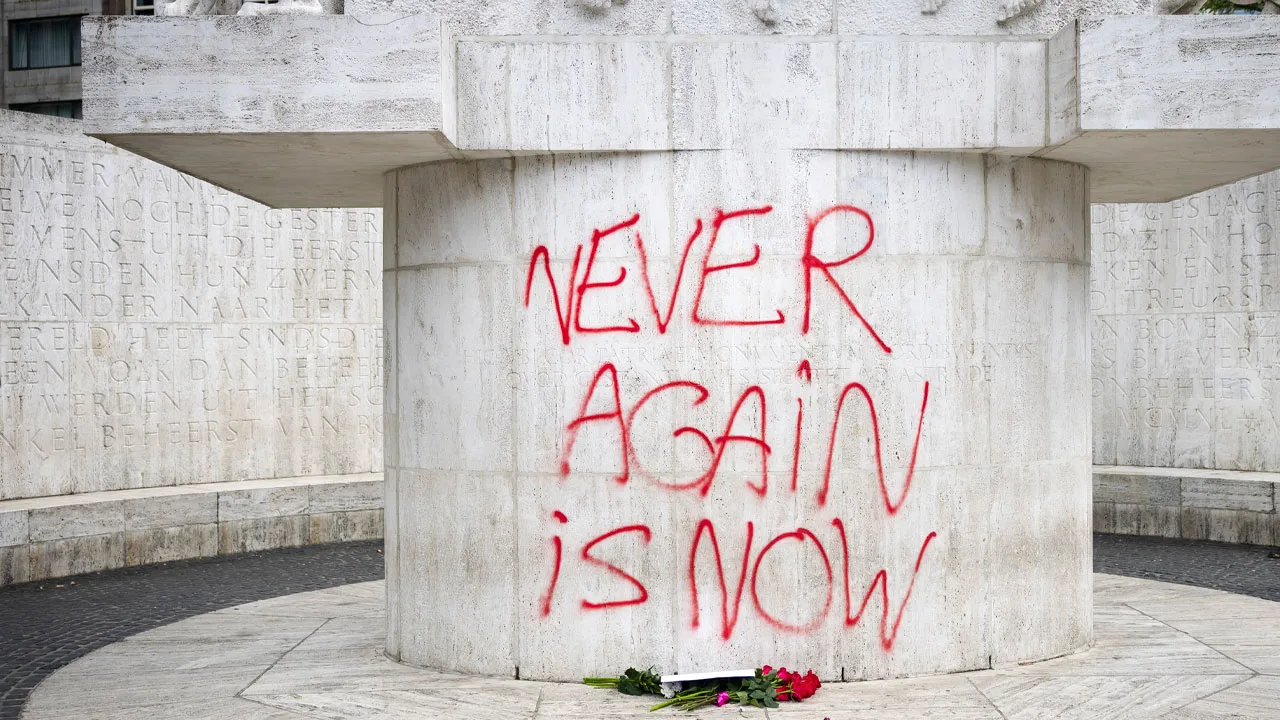 Betoger spuit leus op Monument op de Dam tijdens demonstratie