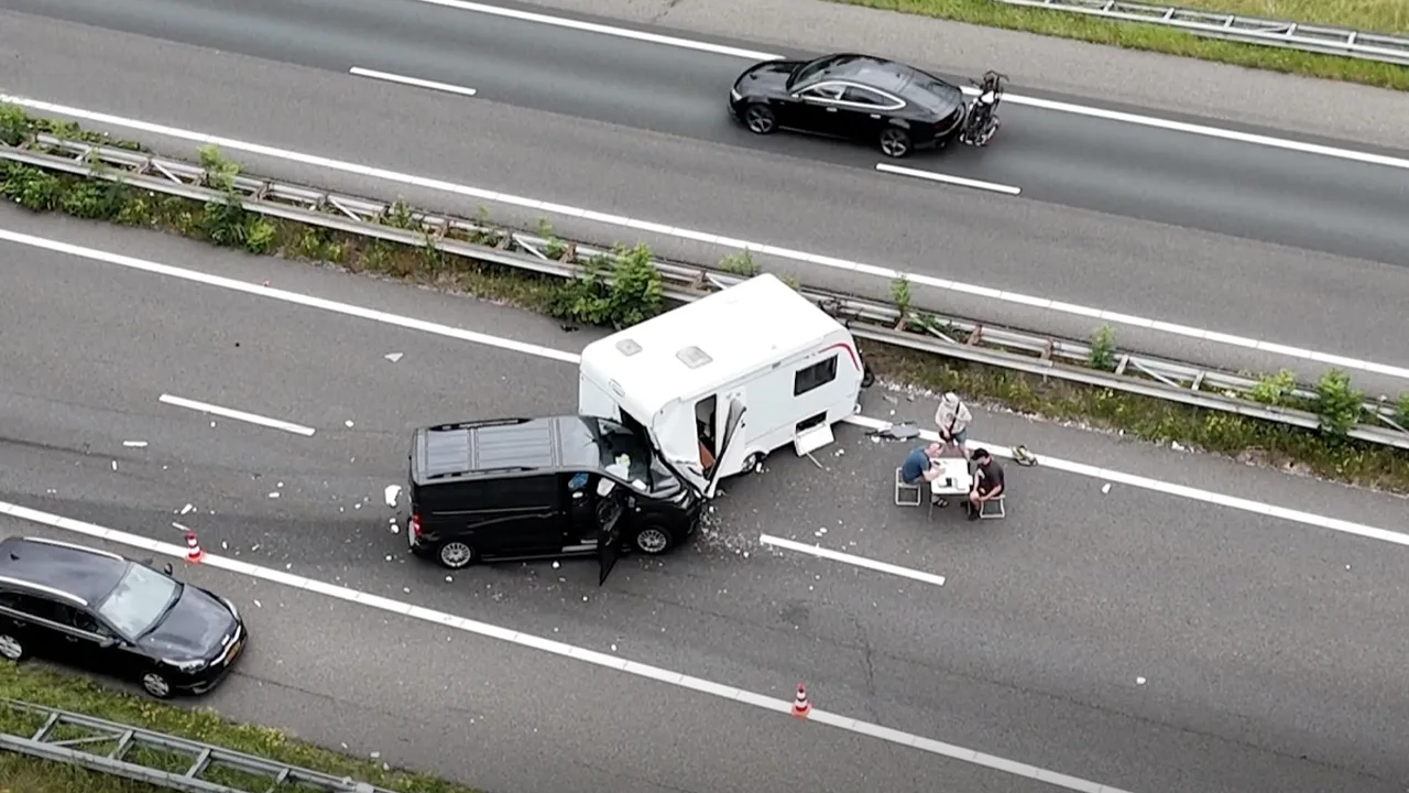 Auto botst op caravan, papieren worden ingevuld aan campingtafel op snelweg
