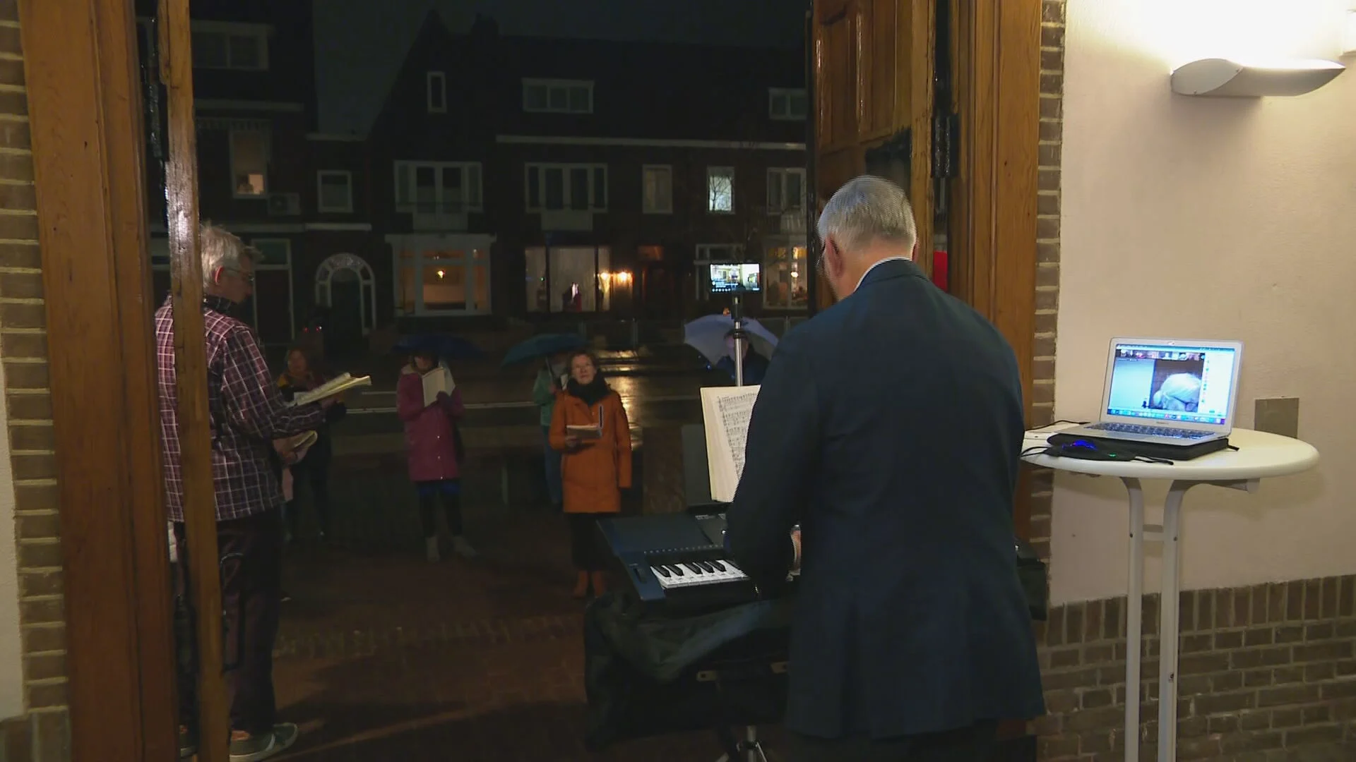 Tijdens de persconferentie repeteert dirigent Robert in de buitenlucht met zijn koor