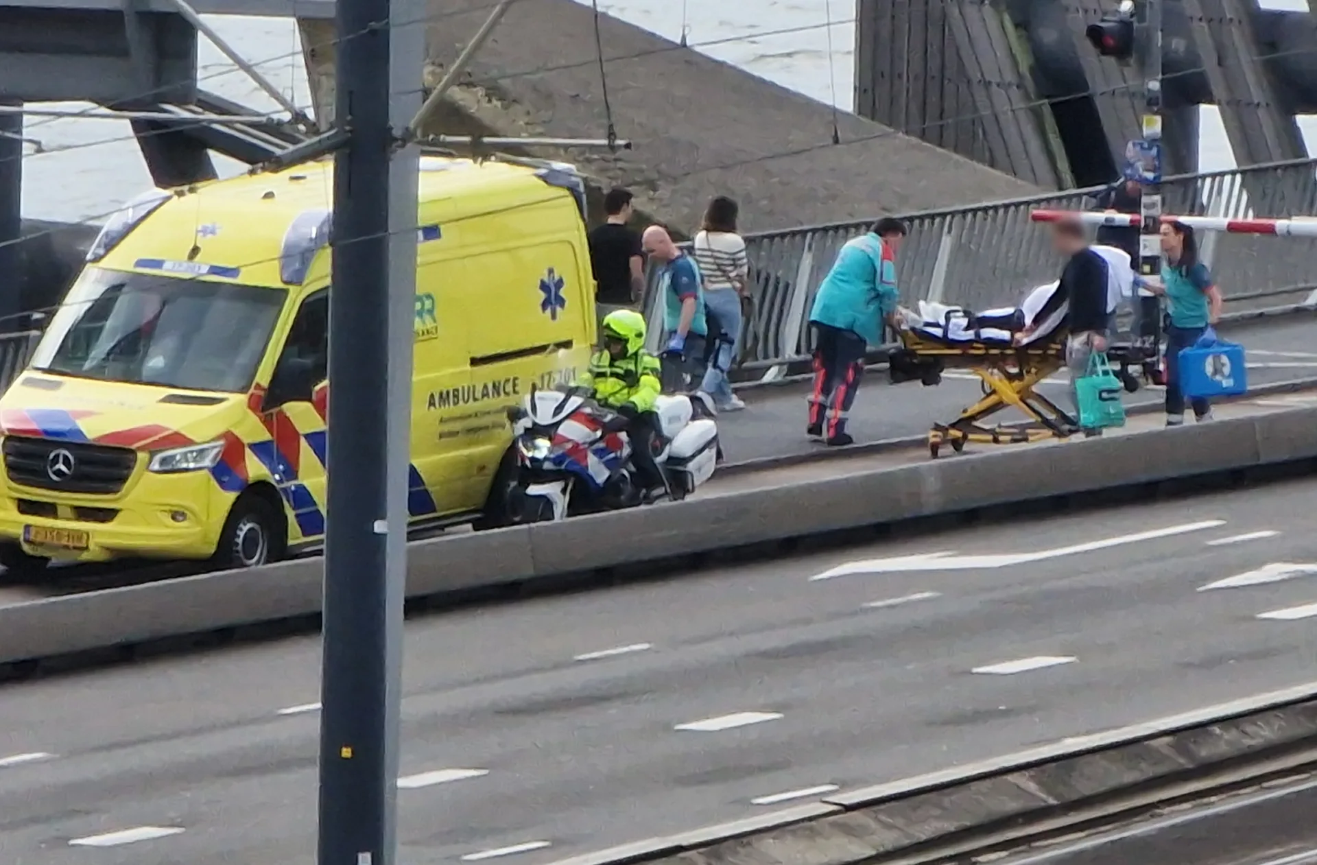 Bevallende vrouw op brancard onder slagbomen Erasmusbrug geduwd