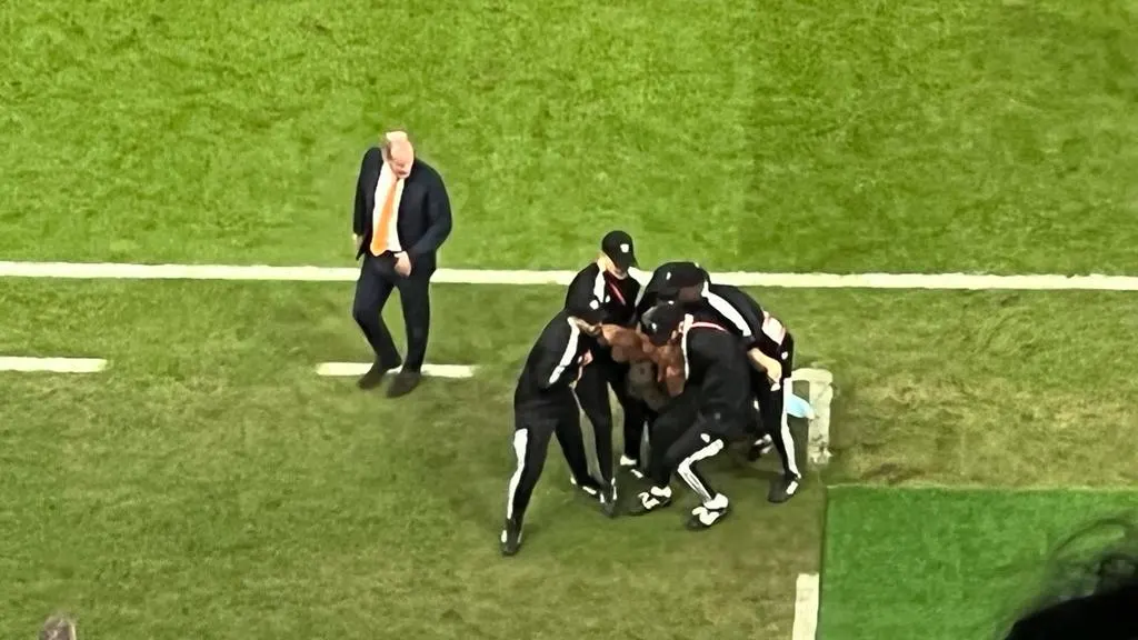 Supporter rent veld op tijdens kwartfinale van Oranje op WK, vier man dragen hem weg