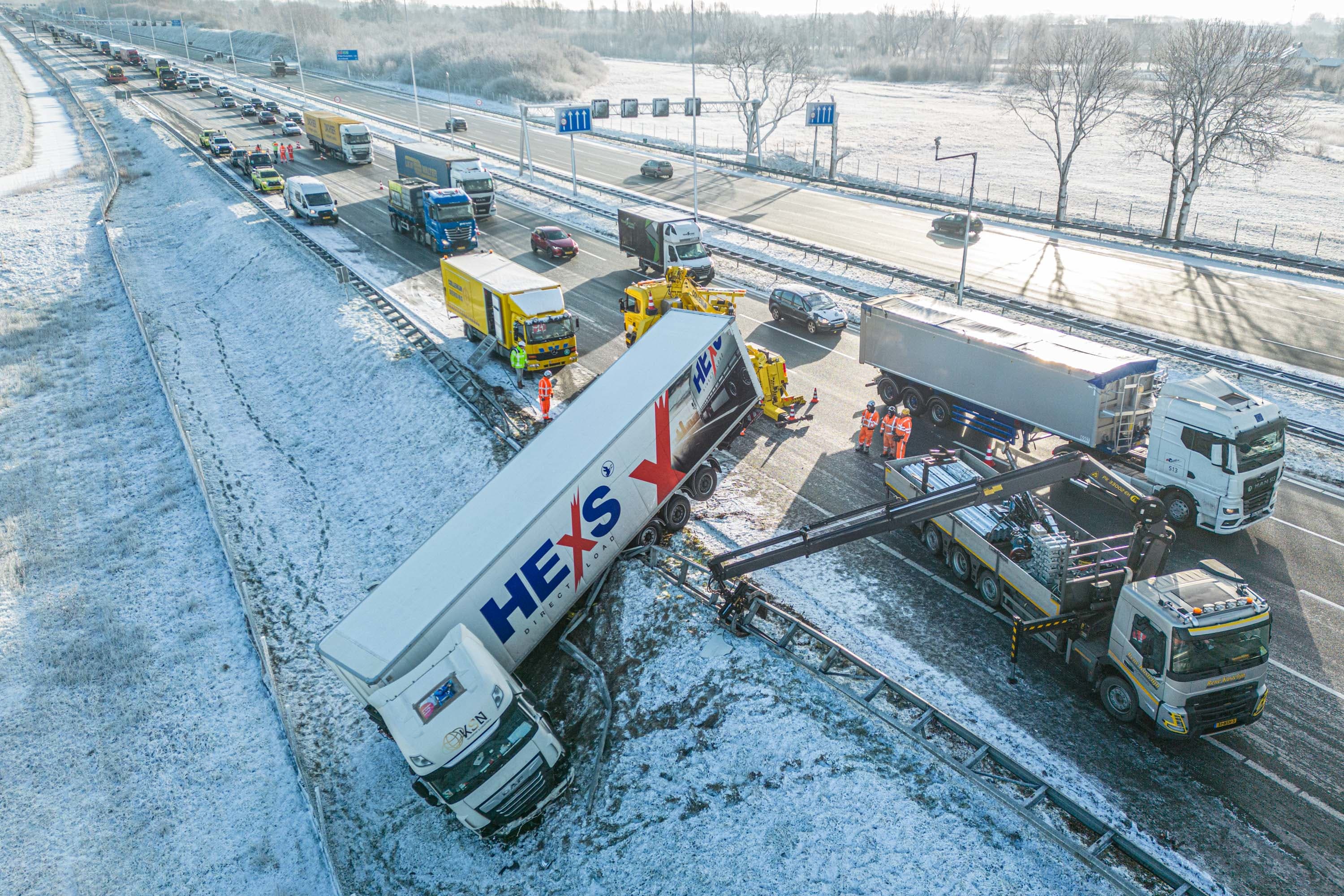 Vrachtwagen glijdt van de weg en schiet door vangrail op A12