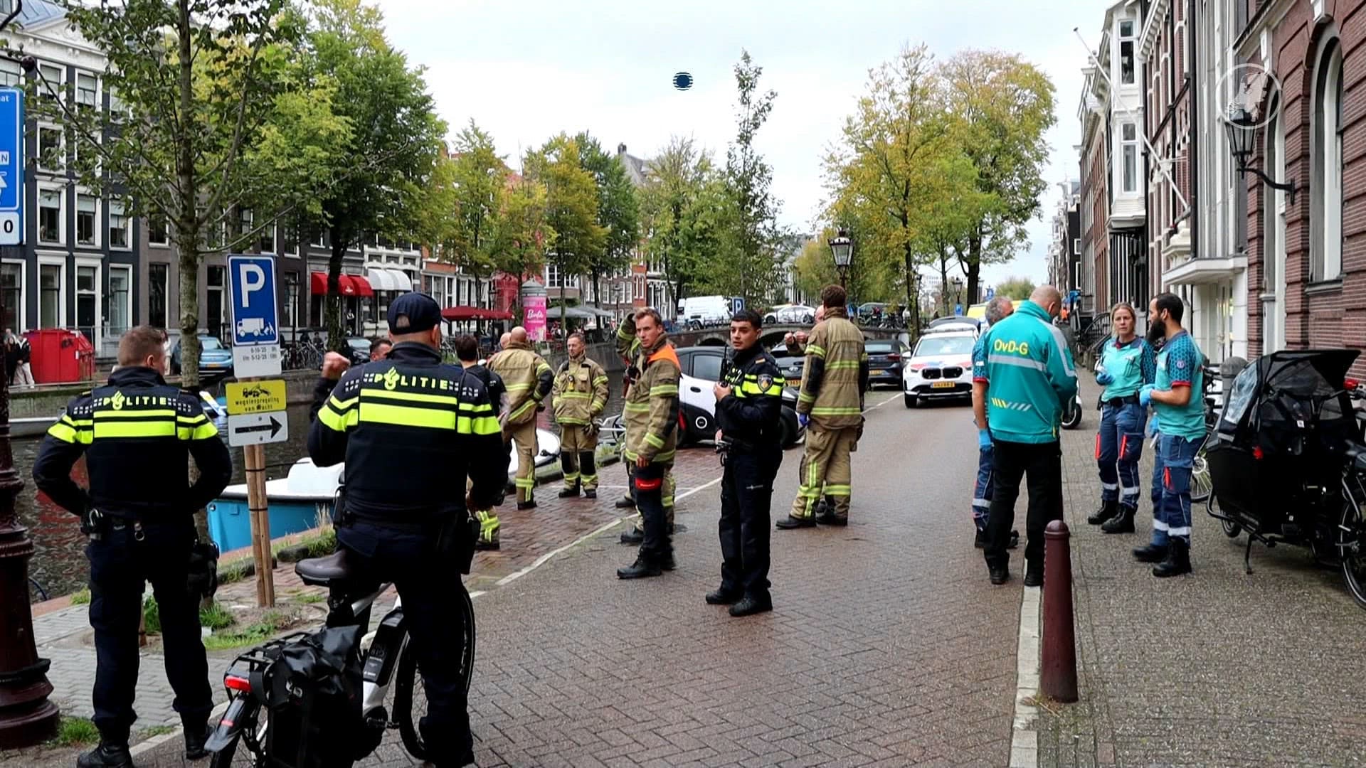Brommobiel rijdt de Herengracht in, omstanders bevrijden moeder en kind.