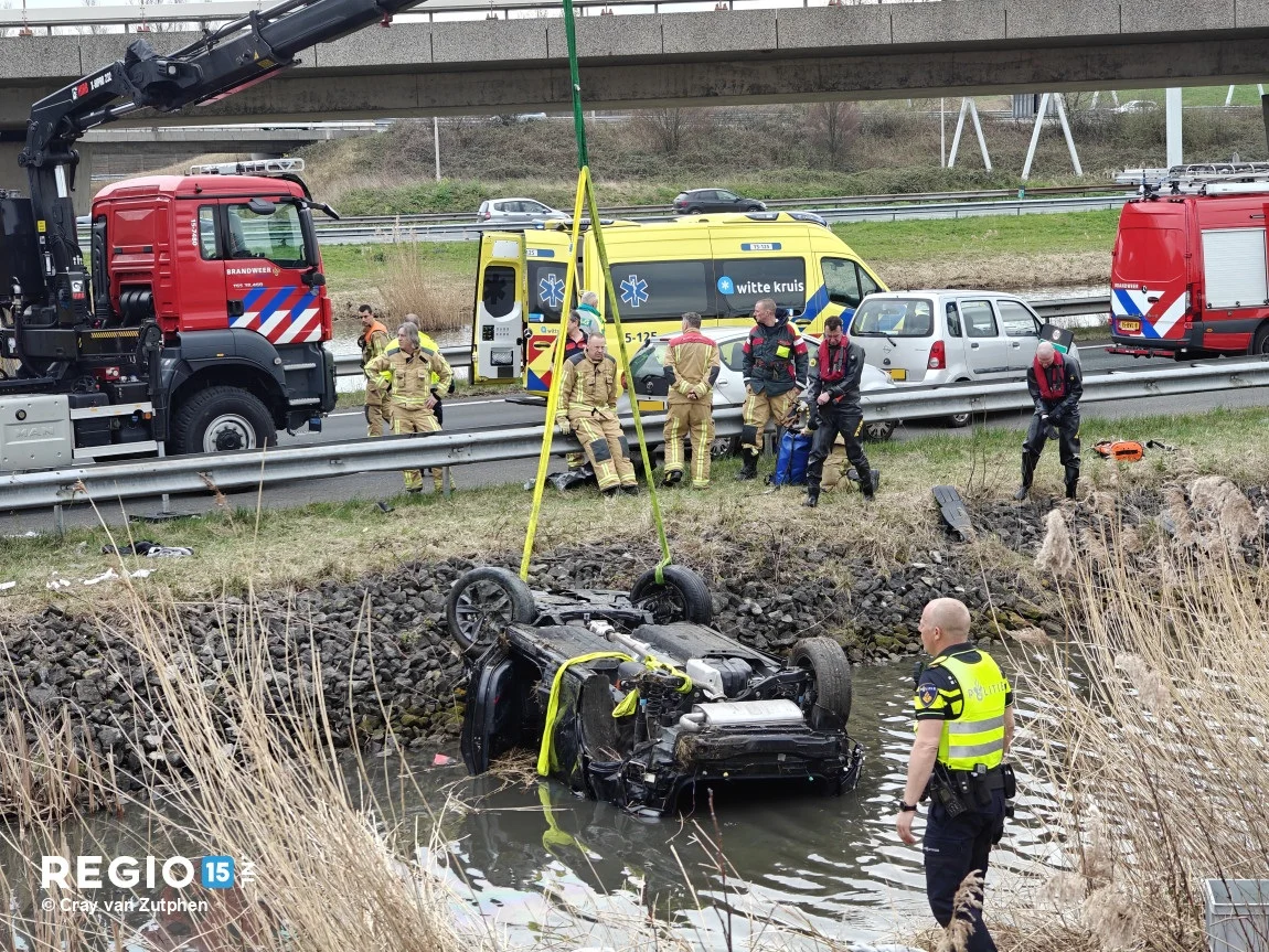 Auto op zijn kop in water op A12, twee personen gewond