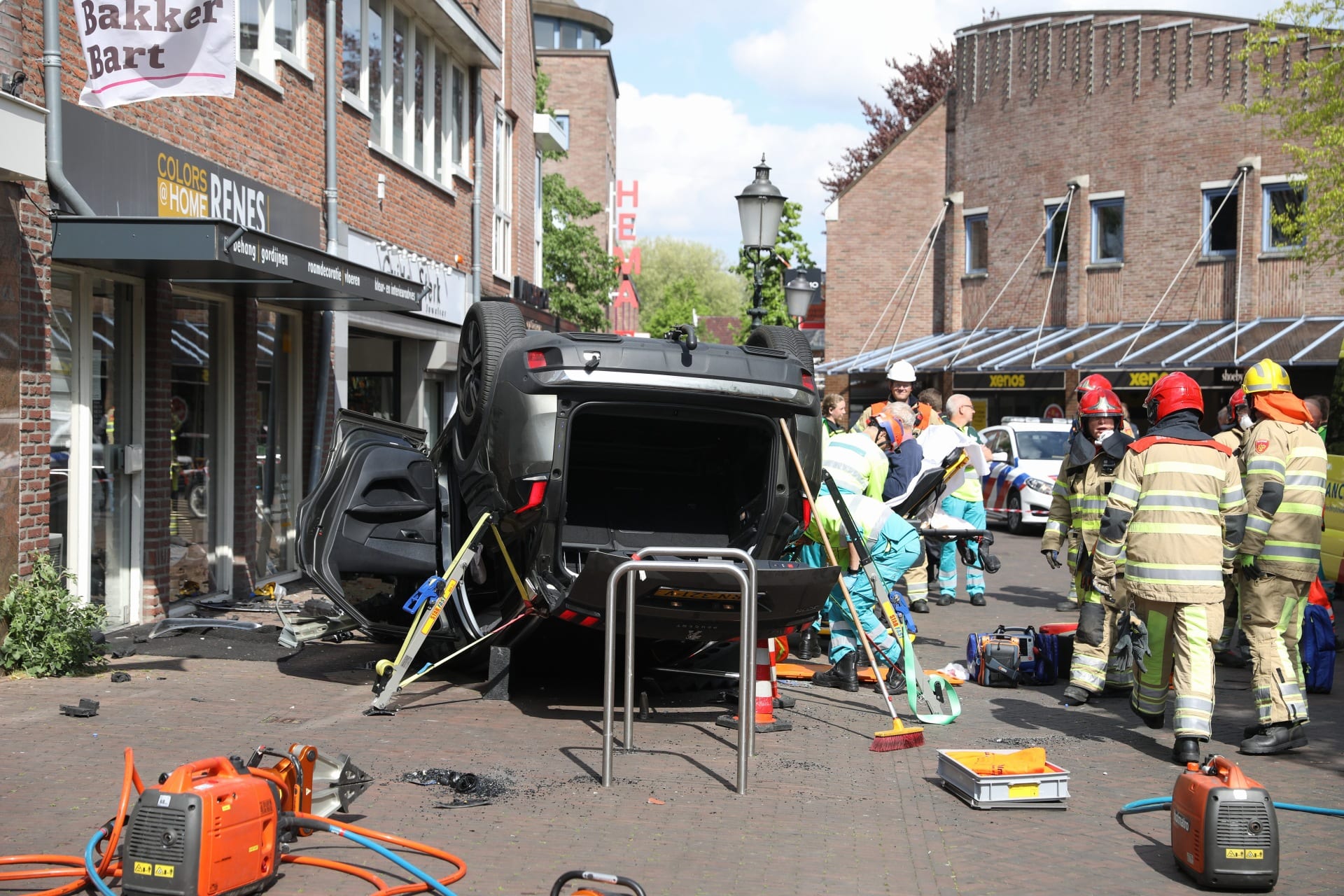 Auto rijdt dwars over plein in Huizen winkel binnen, twee mensen gewond