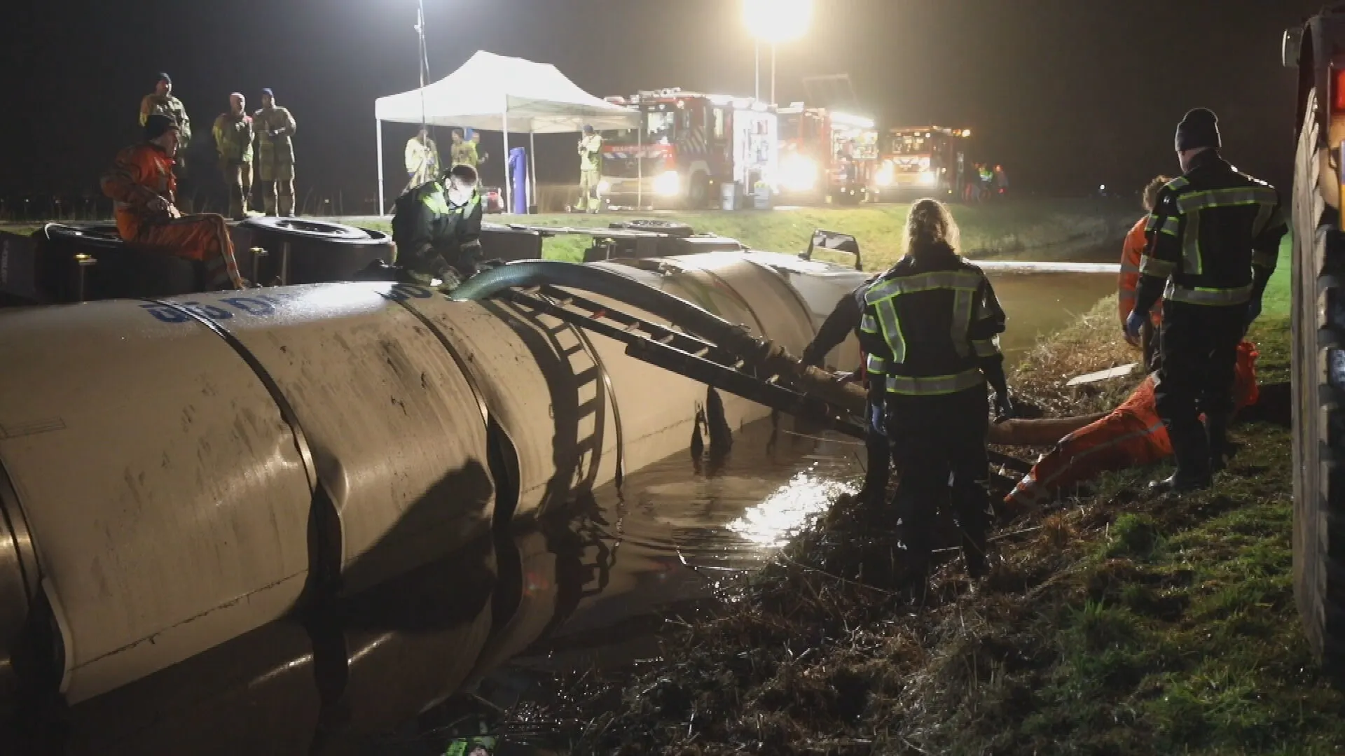 Tankwagen met duizenden liters melk glibbert van de weg en belandt in water