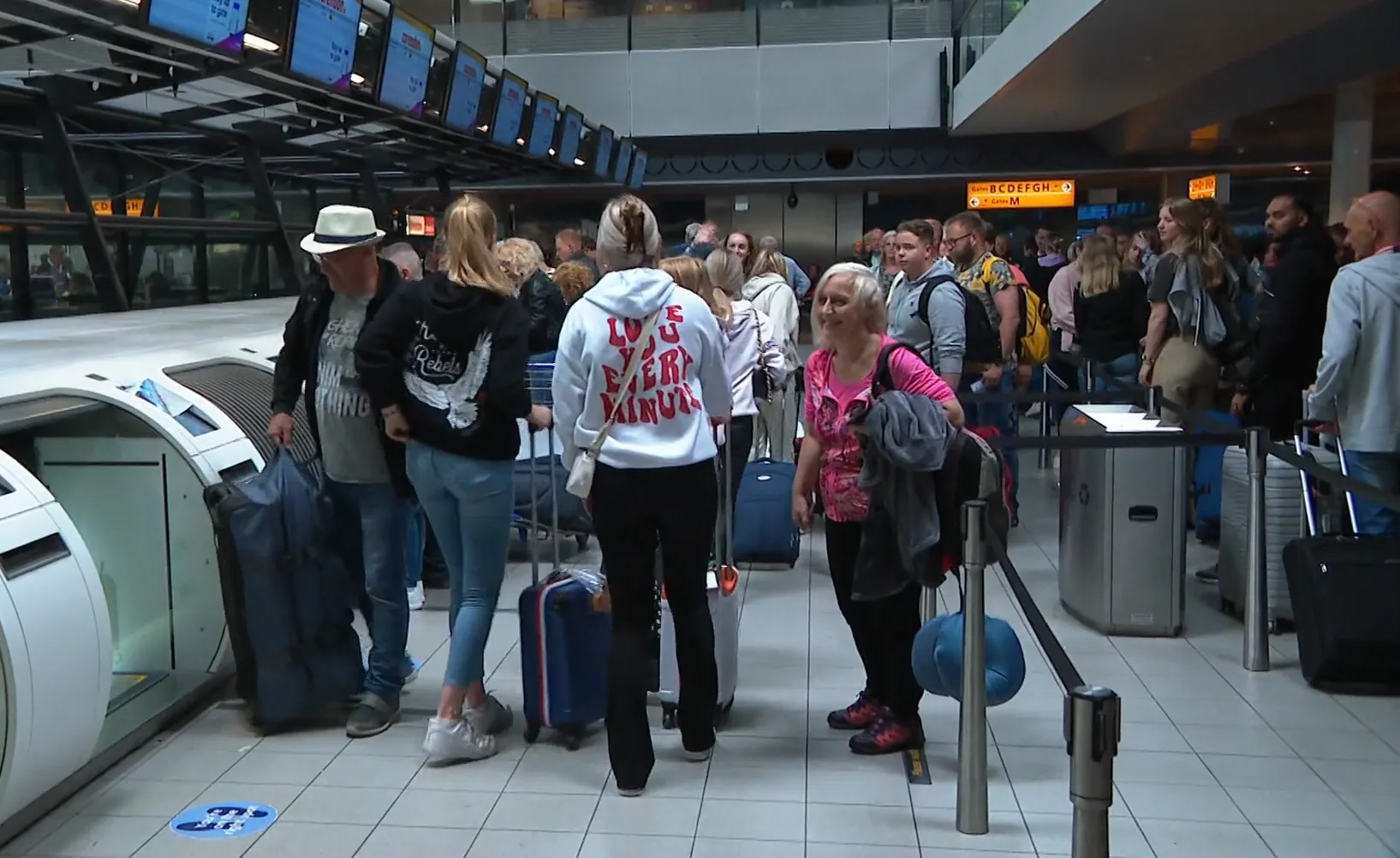 Lange rijen voor de security bij Schiphol, water wordt uitgedeeld