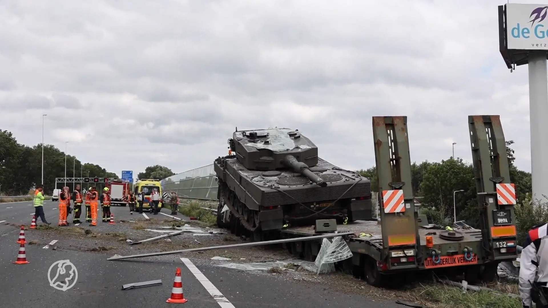 Militaire vrachtwagen met tank knalt door geluidswal op A12