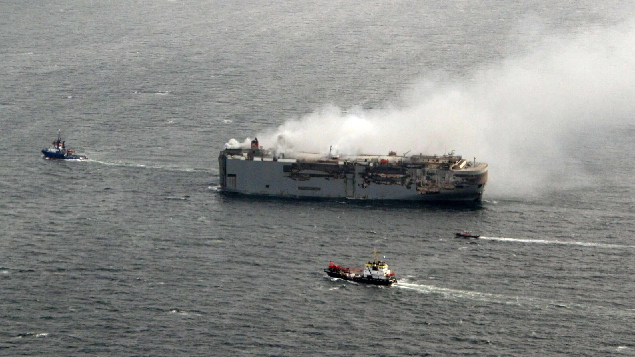 Brandend vrachtschip langzaam naar nieuwe locatie