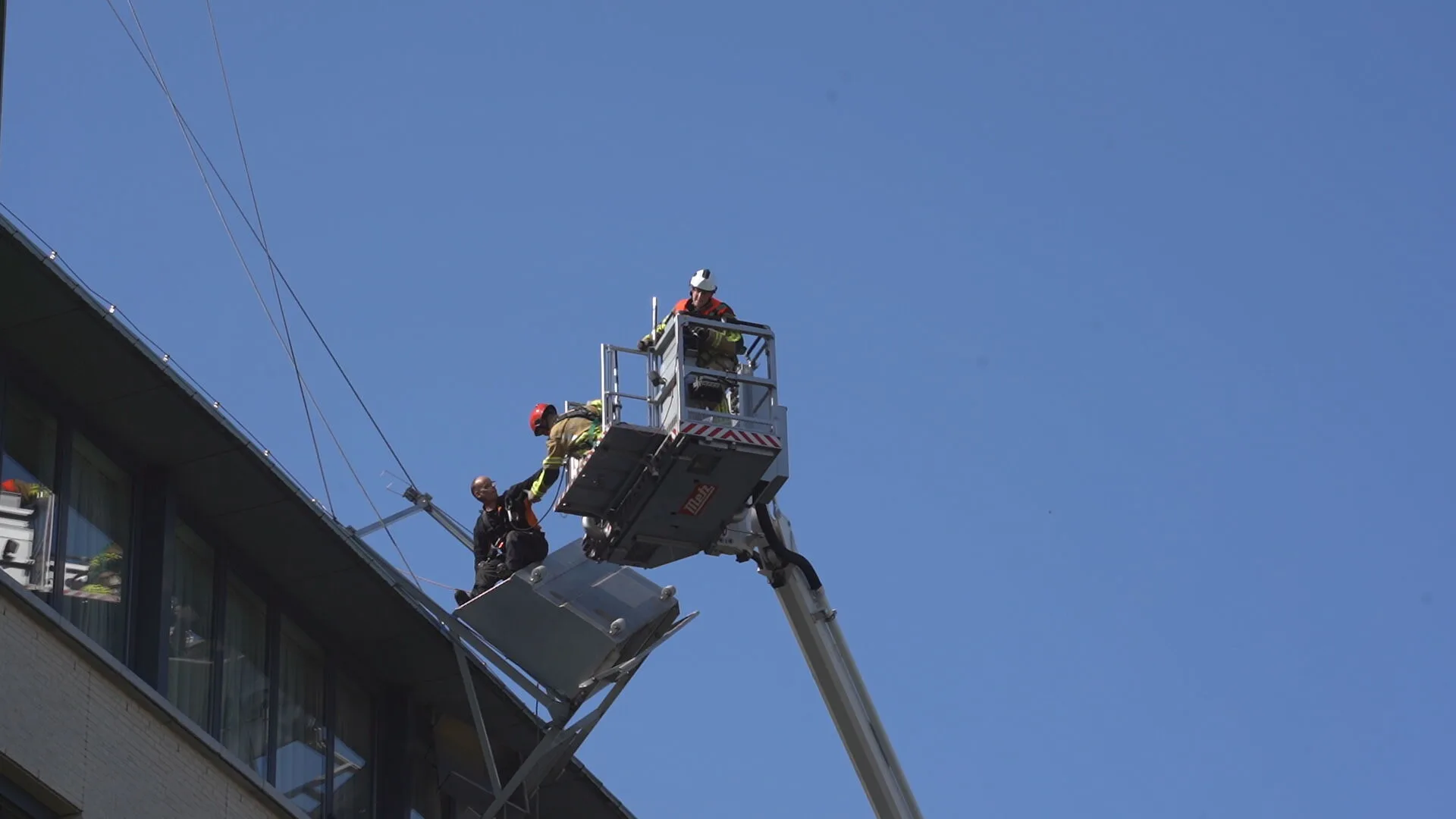 Brandweer plukt ondersteboven bungelende glazenwasser van dakgoot