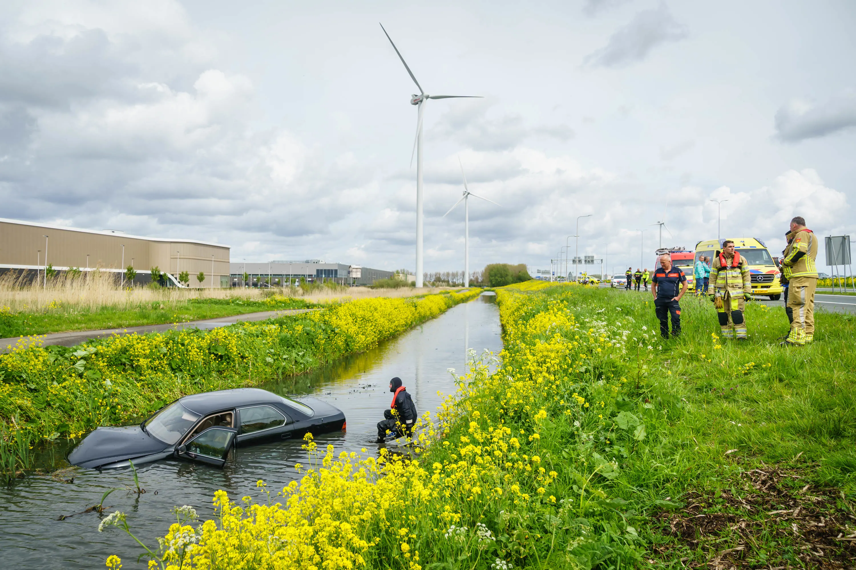 Omstanders springen water in om automobilist te redden