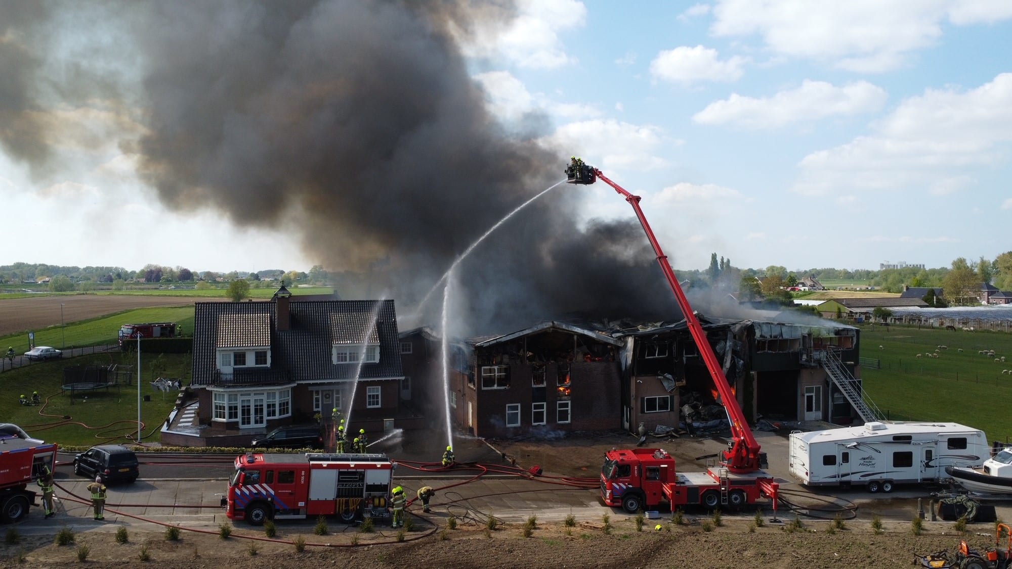 Grote uitslaande brand bij transportbedrijf aan Maasdijk in Poederoijen
