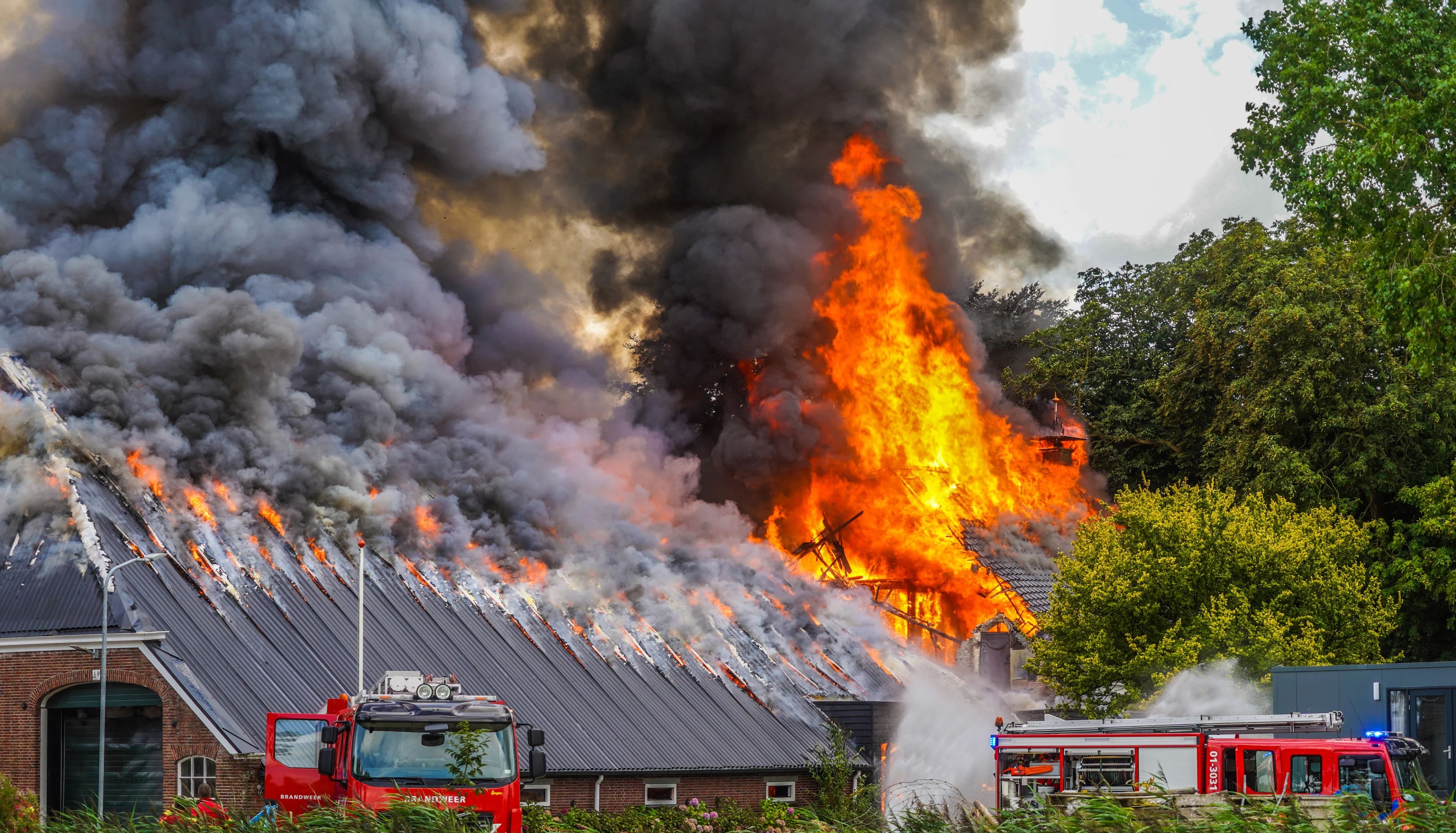 Grote brand legt loods in as, brandweer probeert woning te redden