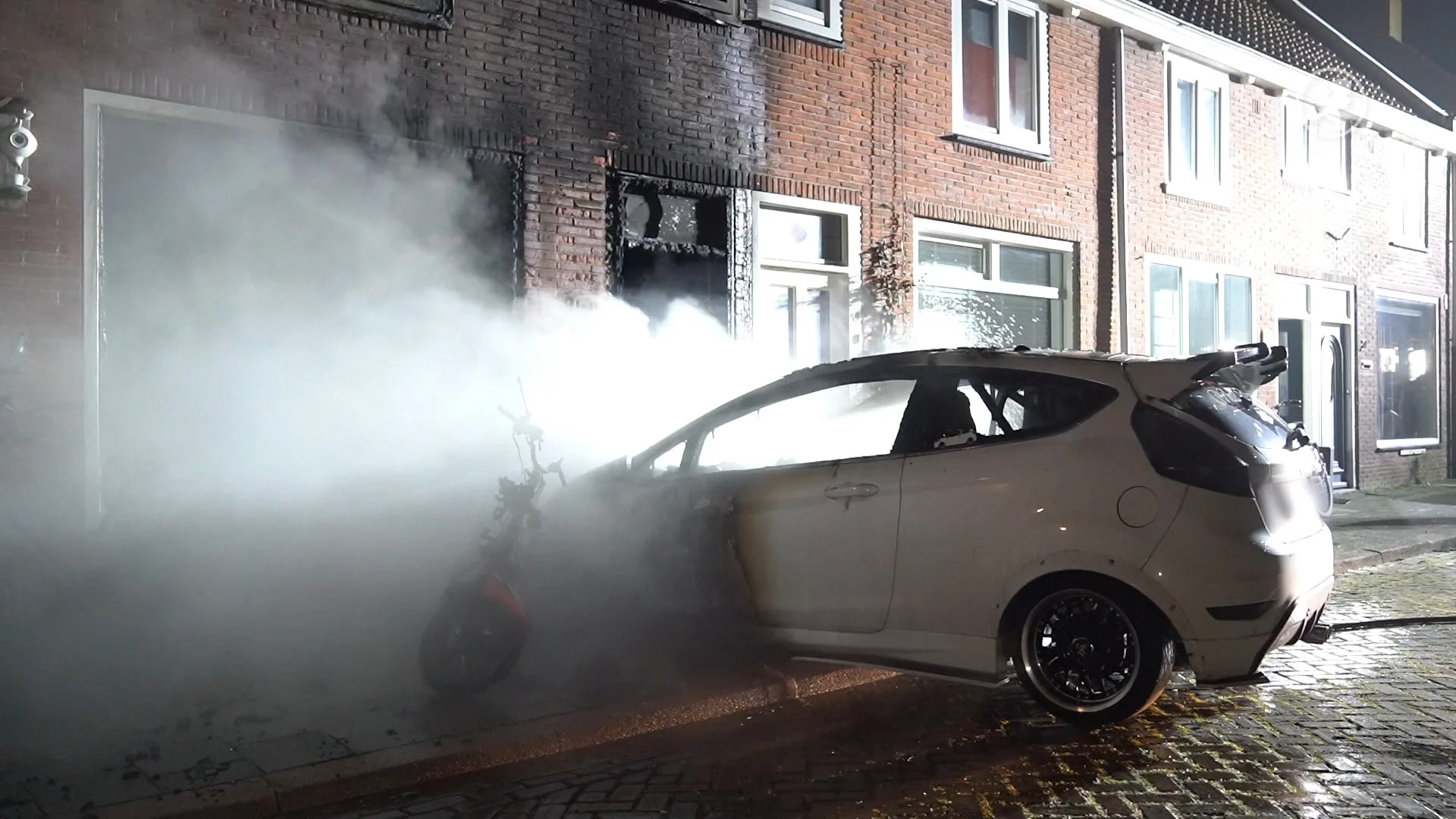 Brandende auto knalt tegen woonhuis, enorme schade aan gevel 