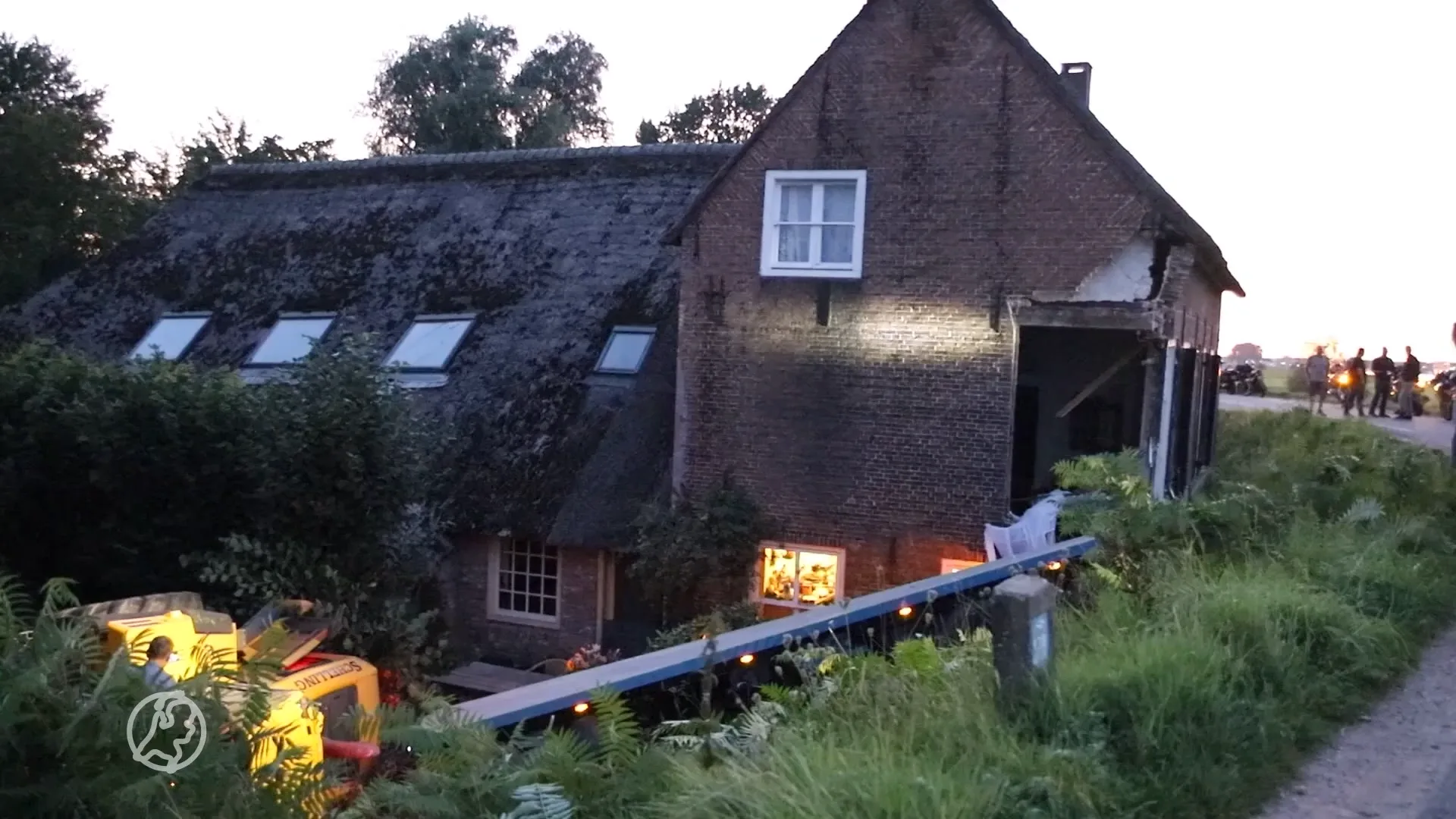 Shovel rijdt dijk af en boort zich door woonkamer van huis