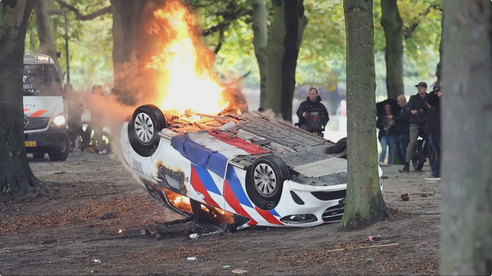 Bij het Malieveld in Den Haag ligt een brandende politieauto op de kop. Beeld: Regio15.