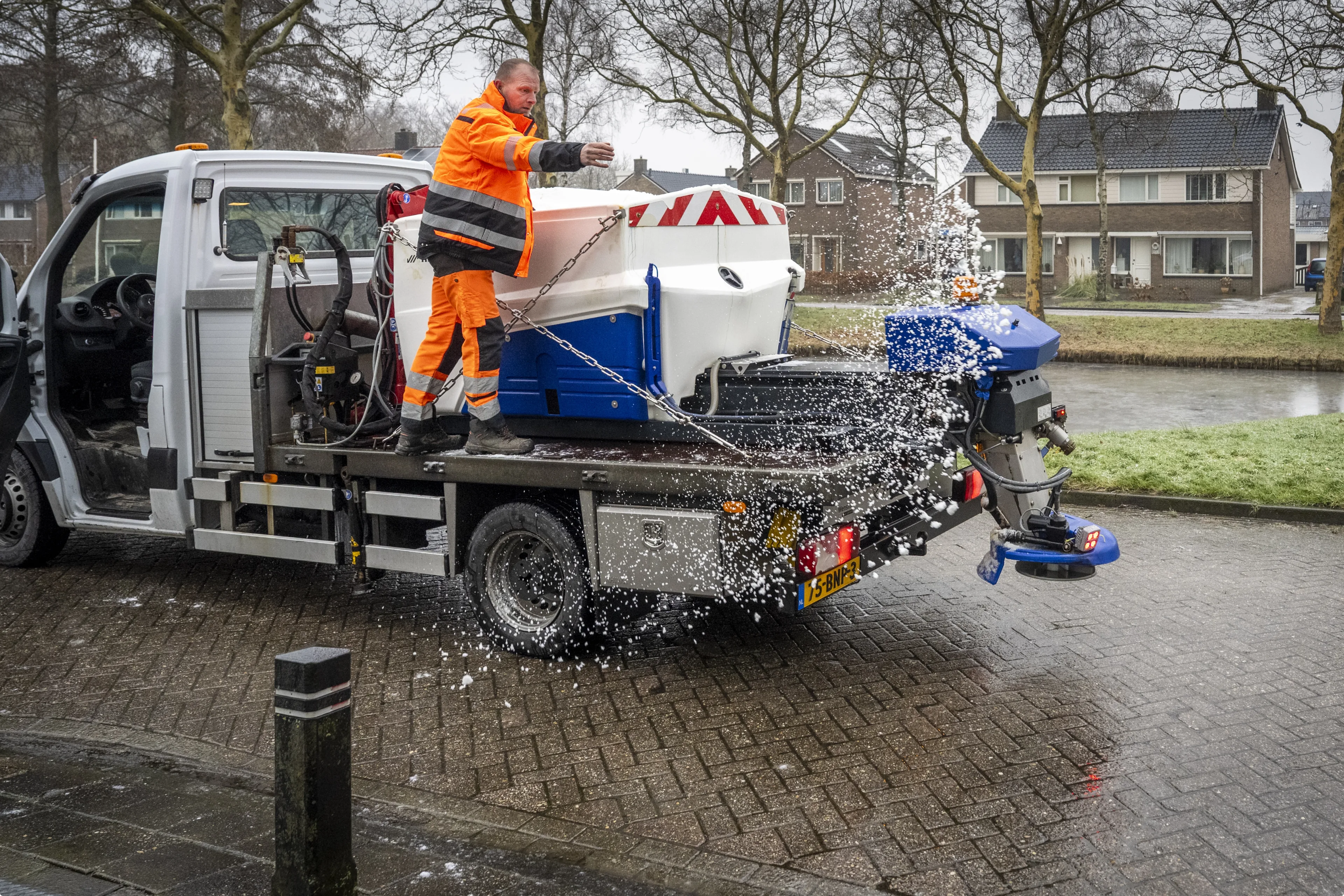 Een gemeenteambtenaar probeert met wat zout een vastzittend busje te helpen. Beeld: ANP